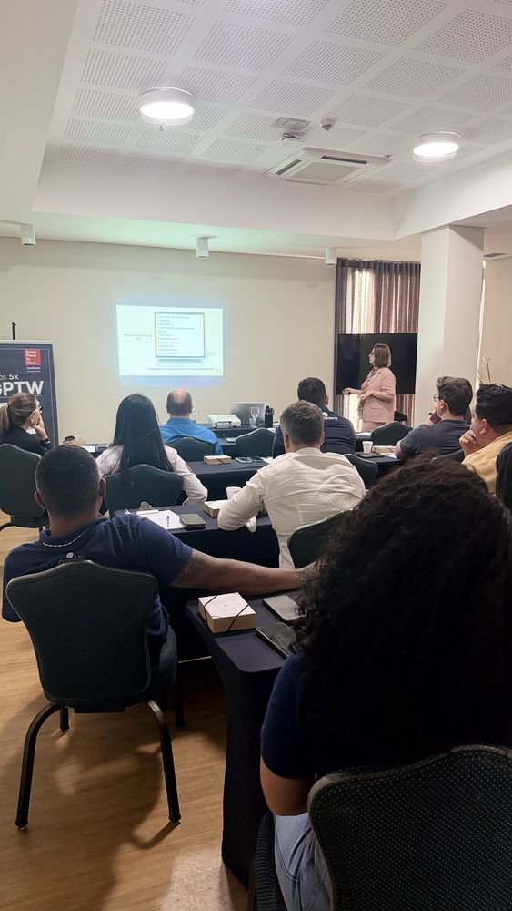 Sala de treinamento com a equipe assistindo à apresentação